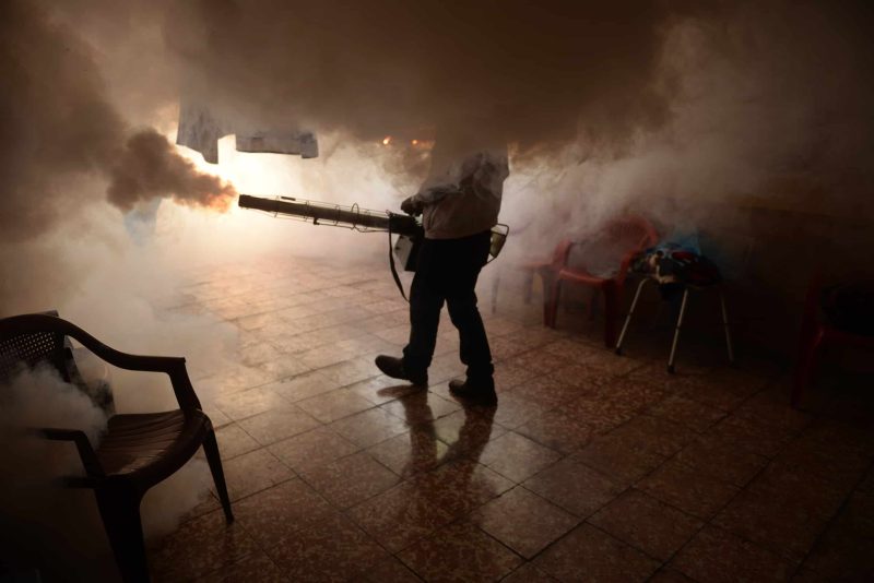 A man spraying pesticides in a closed building