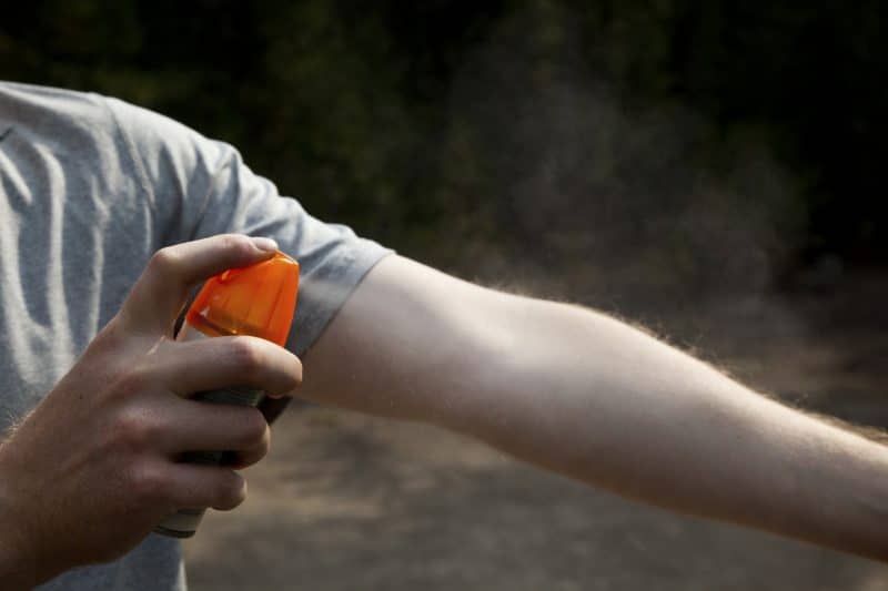 Man spraying on DEET insect repellent