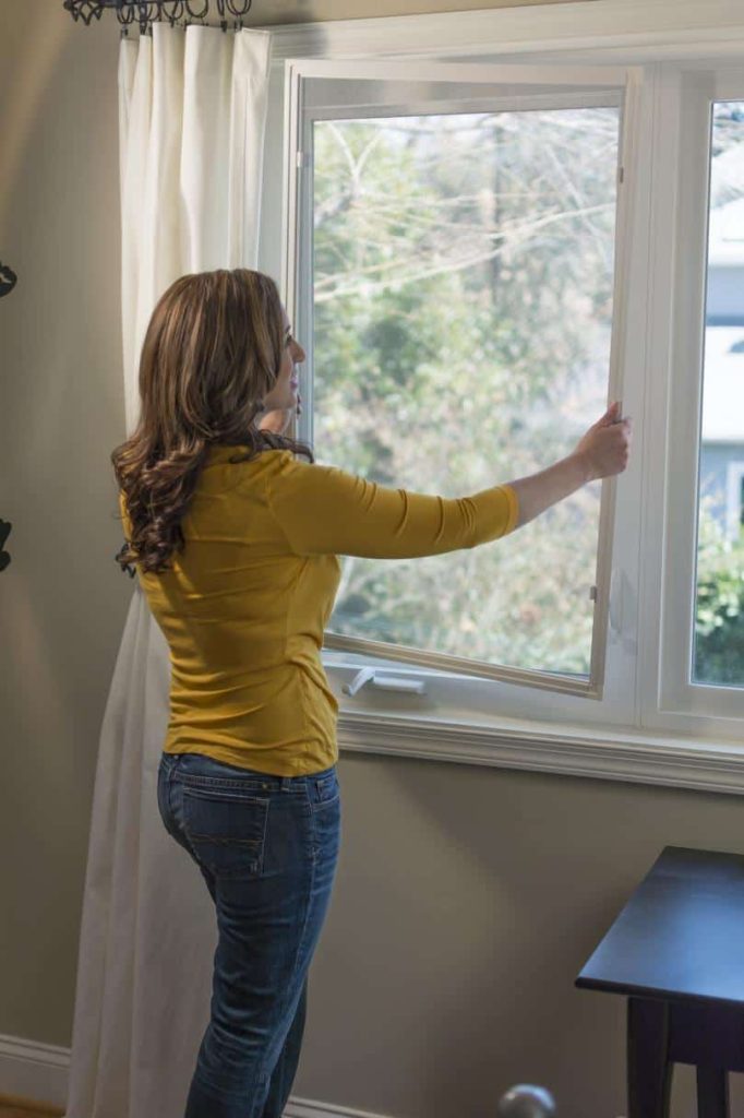 Woman installing a window screen to repell gnats